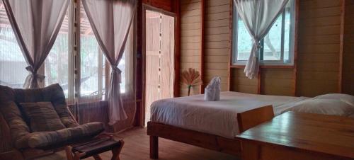 a bedroom with a bed and a couch and windows at Lazy Hut in Ko Phayam