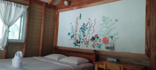 a bedroom with a painting of flowers on the wall at Lazy Hut in Ko Phayam
