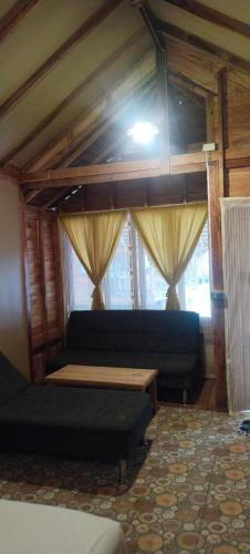 a living room with a blue couch and windows at Lazy Hut in Ko Phayam