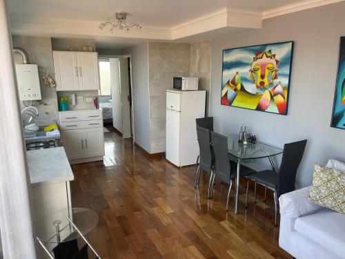 a kitchen and a living room with a table and a refrigerator at Lujoso departamento en ¨torre Alessandria¨ in Cochabamba