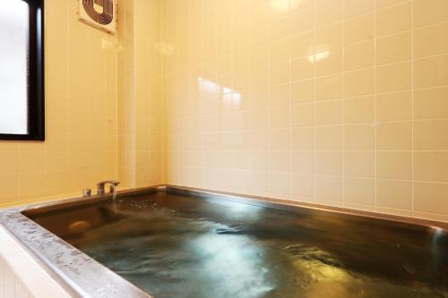 a bath tub filled with water in a bathroom at 民宿ふくだ in Minamiōsaka