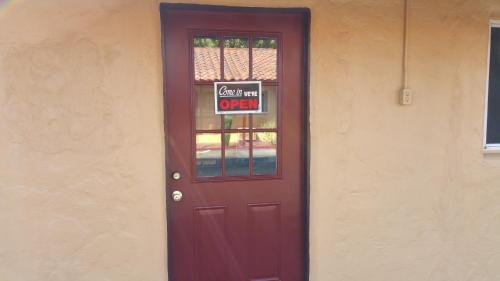 a red door with a sign that says open at Slumber Motel in Merced