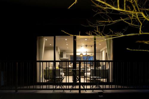 a balcony with a table and chairs at night at 源泉かけ流し 白濁 Forest Suite Hakone Sengokuhara in Sengokuhara