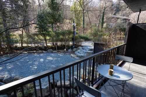 a balcony with a table and a view of a yard at 源泉かけ流し 白濁 Forest Suite Hakone Sengokuhara in Sengokuhara