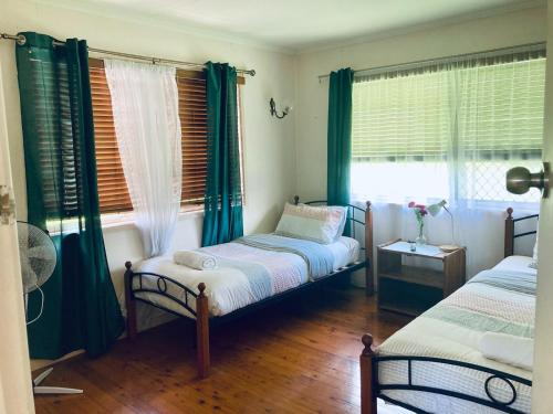 a bedroom with two twin beds and a window at lavender cottage three large bedroom house in Mount Tamborine