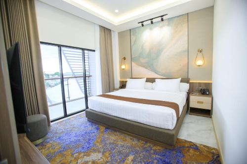 Two K Azana Style Hotel Bengkulu في بنجكولو: غرفة نوم بسرير كبير ونافذة كبيرة