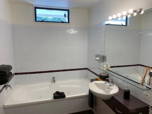 a white bathroom with a tub and a sink at Academy Motor Inn in Tauranga