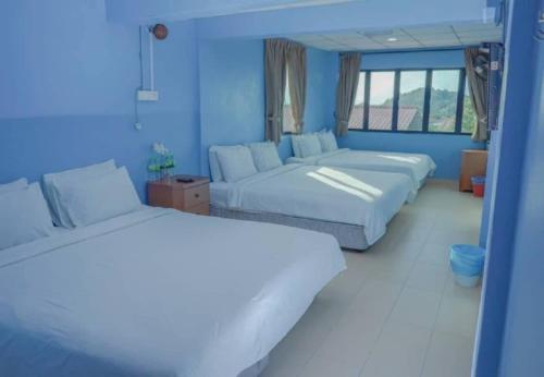 twee bedden in een kamer met blauwe muren bij LABIS SUNRISE FARM STAY in Labis