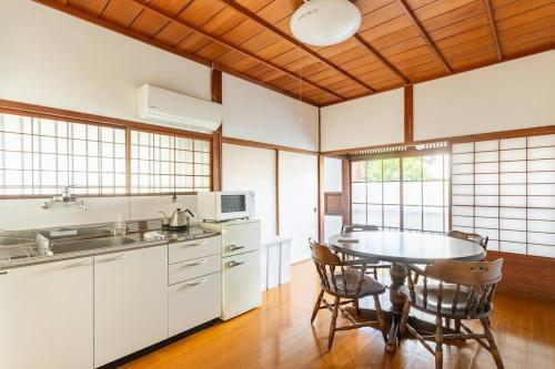 a kitchen with a table and chairs in a room at 日々の宿: 宇野駅から車で5分 直島へ 最大7名様 古民家貸切 一棟貸し in Tama