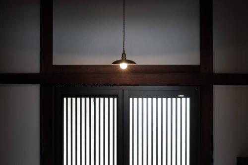 にある日々の宿: 宇野駅から車で5分 直島へ 最大7名様 古民家貸切 一棟貸しの窓付きの扉に吊るされたペンダントライト