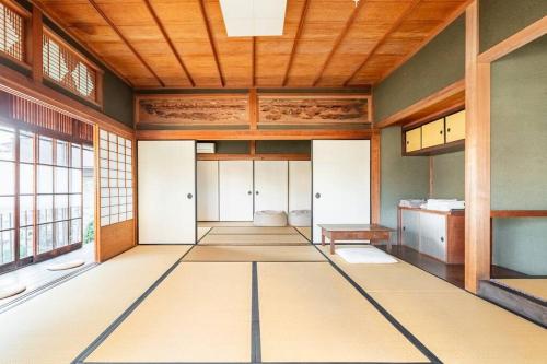 an empty room with wooden ceilings and a large window at 日々の宿: 宇野駅から車で5分 直島へ 最大7名様 古民家貸切 一棟貸し in Tama