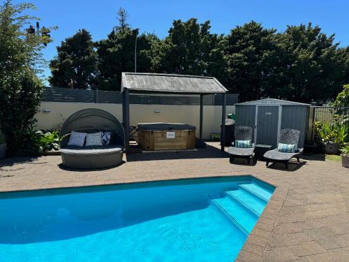 a swimming pool with two chairs and a gazebo at Academy Motor Inn in Tauranga
