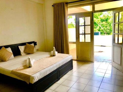 a bedroom with a bed and a sliding glass door at Hotel Nathaliya in Seeduwa