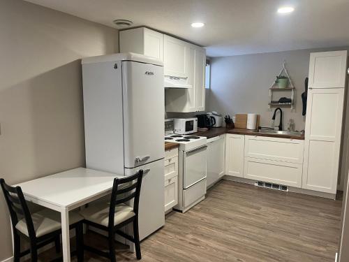 a kitchen with a white refrigerator and a table and chairs at Entire Basement Guest Suite In Cranbrook in Cranbrook