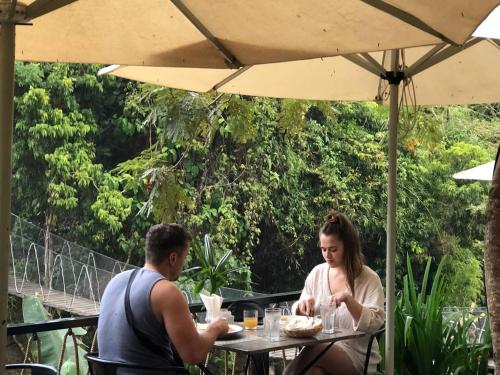 a man and a woman sitting at a table under an umbrella at Green Valley Veal Pouch in Kampot