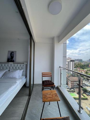 a bedroom with a bed and a chair on a balcony at Comfy studio near yaya Kilimani in Nairobi