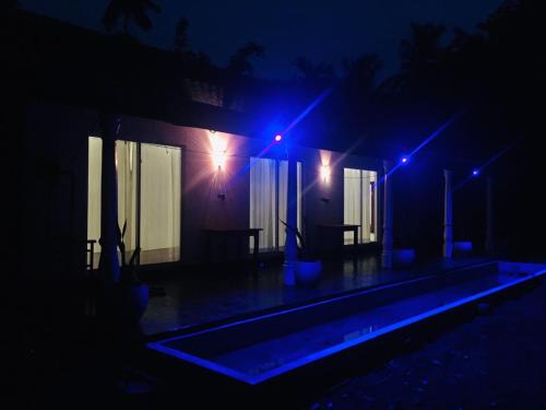 a house with a swimming pool at night with blue lights at Happy Three Holiday Homes in Hikkaduwa