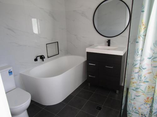 a bathroom with a tub and a sink and a toilet at Seaview Retreat in Tiddy Widdy