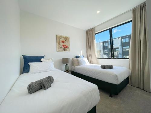 a hotel room with two beds and a window at Your Modern Home in Sandringham, Close to City, Heat Pumps, Netflix, Parking in Auckland