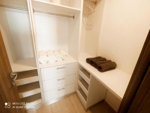 a walk in closet with white cabinets and towels at estancia de playa y golf in Punta Cana