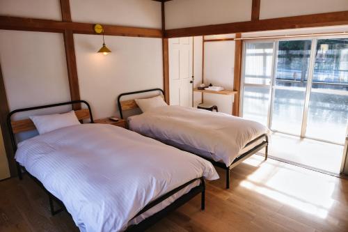 two beds in a room with a large window at palette in Numazu