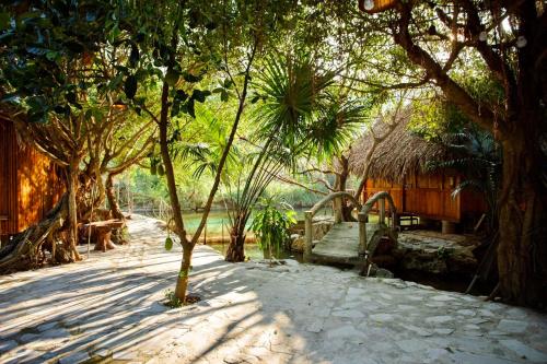 a resort with trees and a bench and a building at Hang Lan Bungalow in Ninh Binh