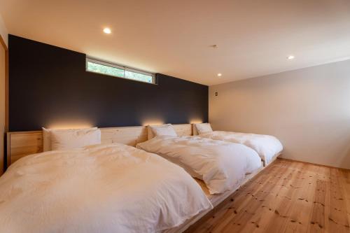 two beds in a bedroom with a window on the wall at 一棟貸切Azumino36Stay 安曇野の静かな隠れ家 貸切サウナ BBQ 絶景テラス in Azumino