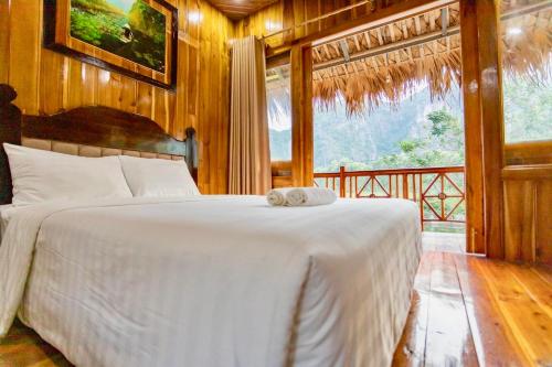 ein Schlafzimmer mit einem Bett und einem großen Fenster in der Unterkunft Hang Lan Bungalow in Ninh Bình