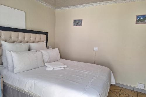 a white bed with a white towel on it at Maluti Backpackers in Phuthaditjhaba
