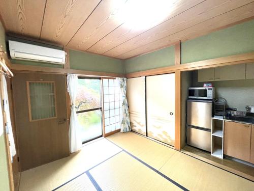 an empty room with a kitchen with a microwave at Inn Unkai no Sato no Yado 民宿 雲海の里の宿 in Nosegawa
