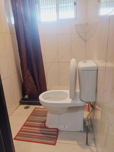 a bathroom with a toilet with a window and a rug at Double bed in Nadi