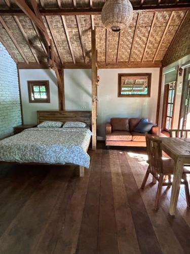 een slaapkamer met een bed, een bank en een tafel bij Santai House in Tetebatu