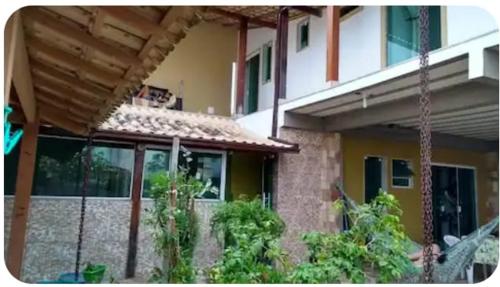 een huis met een veranda en een gebouw bij Tia Rosi tem suite independente 200mts da praia c ar e energia solar c atendimento vip in Rio das Ostras