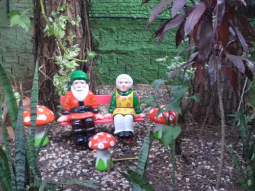 two toy gnomes sitting on a bench in a garden at Pousada Laura / Ziza in Foz do Iguaçu