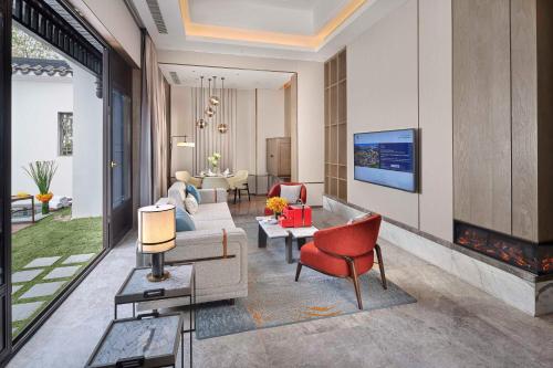 a living room with a couch and chairs and a tv at Doubletree By Hilton Yancheng Dayangwan in Yancheng