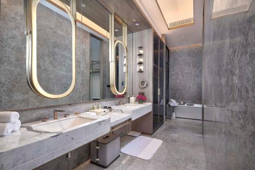 a bathroom with two sinks and two mirrors at Doubletree By Hilton Yancheng Dayangwan in Yancheng