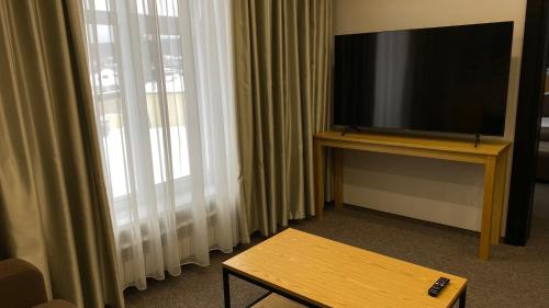 a living room with a flat screen tv and a table at Hotel Burabay in Shchūchīnsk
