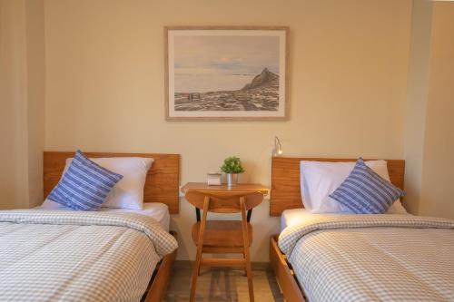 two beds in a room with a table between them at Alba Inn Sanur by SooBali in Sanur