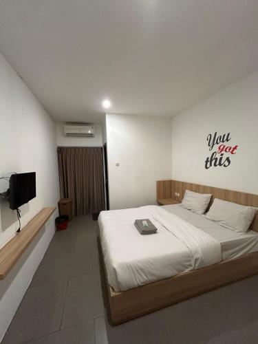 a bedroom with a bed and a tv on the wall at Behomy Maxley Lippo Karawaci in Tangerang