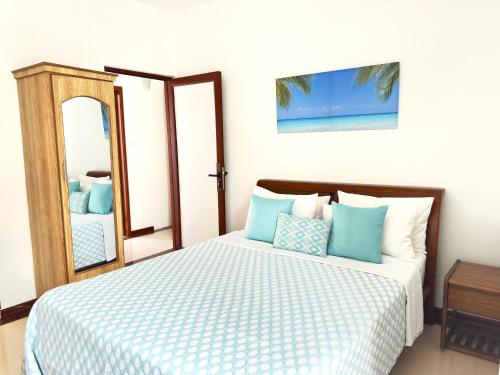 a bedroom with a bed with blue pillows and a mirror at Residence Le Point Choisy in Pointe aux Cannoniers