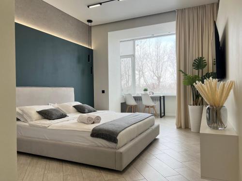 ein Schlafzimmer mit einem großen weißen Bett und einem Tisch in der Unterkunft Апартаменты SMART #9 in Pawlodar