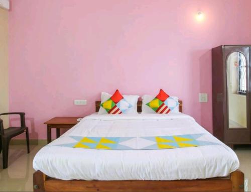 a bedroom with a large bed with pink walls at vyana holiday home in Pernem
