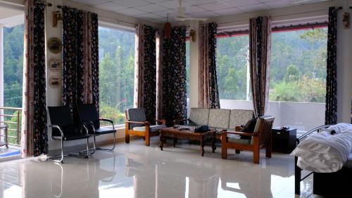 a living room with a couch and chairs and windows at House by the Hills in Dehradun