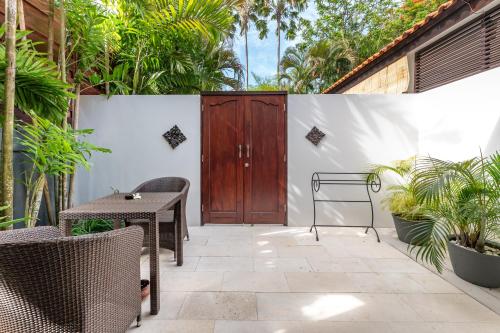 a patio with a wooden door and a table and chairs at Villa Coco Bali in Seminyak