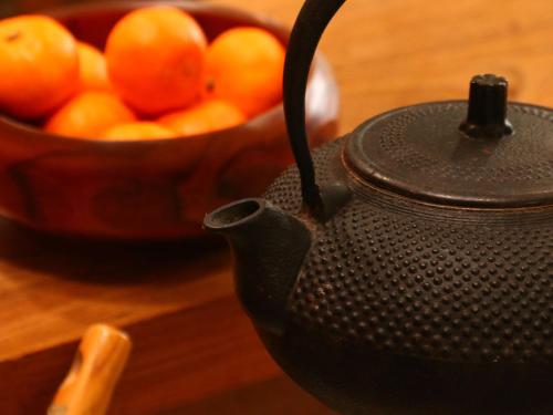a black teapot and a bowl of oranges on a table at Bandai in Tokamachi