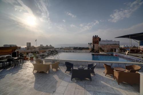 un patio en la azotea con mesas y sillas y una piscina en Mass Boutique hotel, en Áqaba