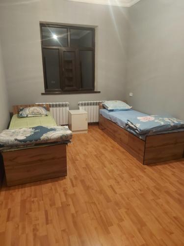 two beds in a room with a wooden floor at munazhat in Türkistan