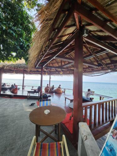 a group of people sitting under a straw hut at the beach at Tao Thong Villa 2 in Ko Tao