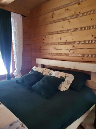 a bed in a room with a wooden wall at domek w zaczarowanym lesie in Istebna