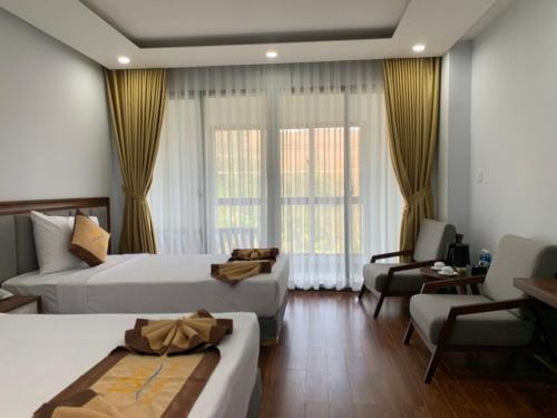 a hotel room with two beds and a chair at Bờ Biển Vàng Resort in Ke Ga